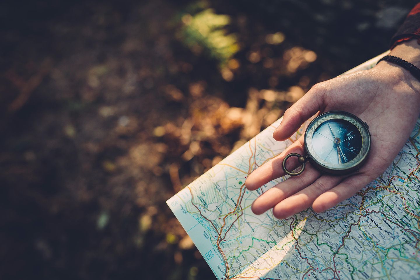 Adolescente con brújula leyendo un mapa en el bosque