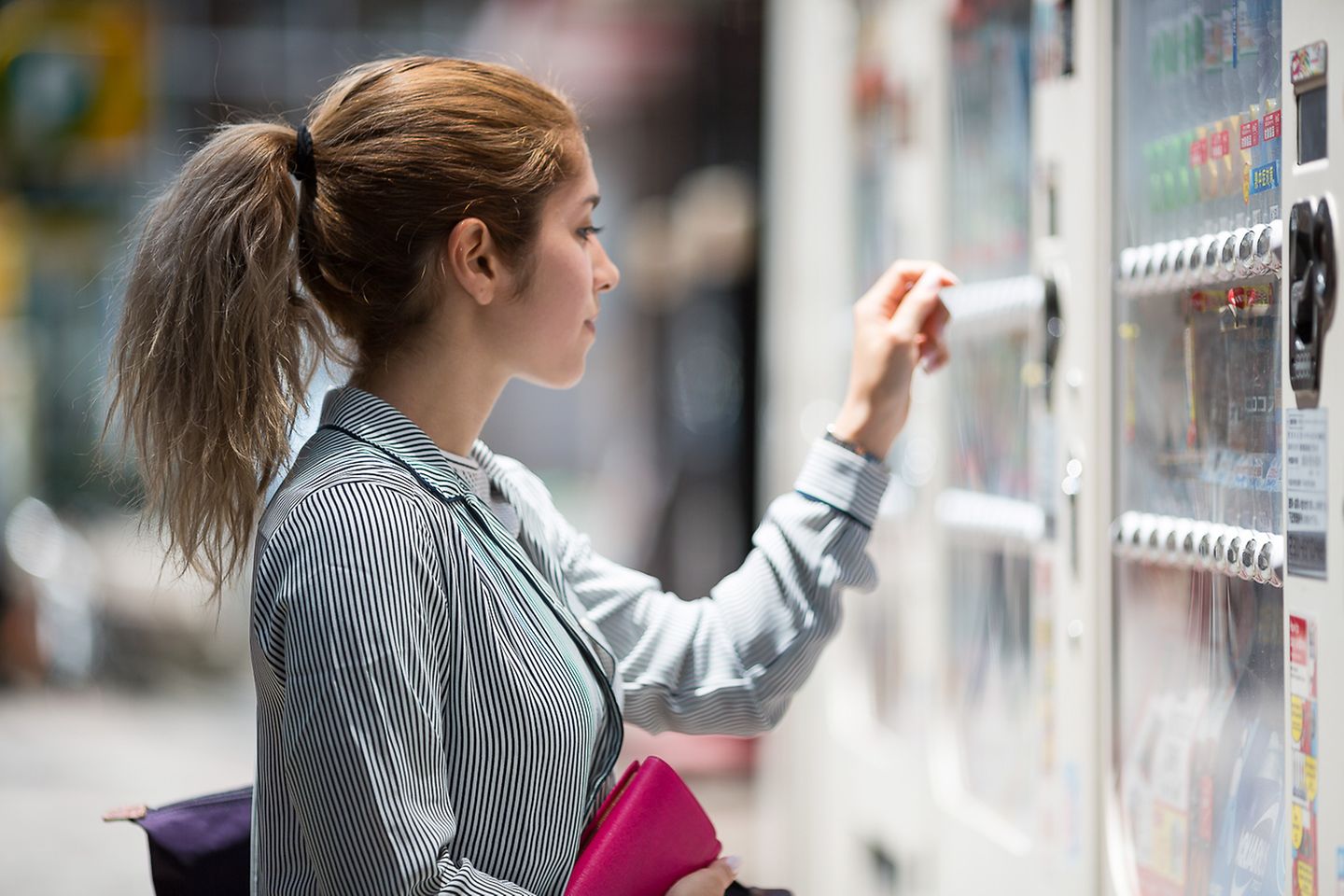 Une femme aux cheveux attachés se tient devant un distributeur