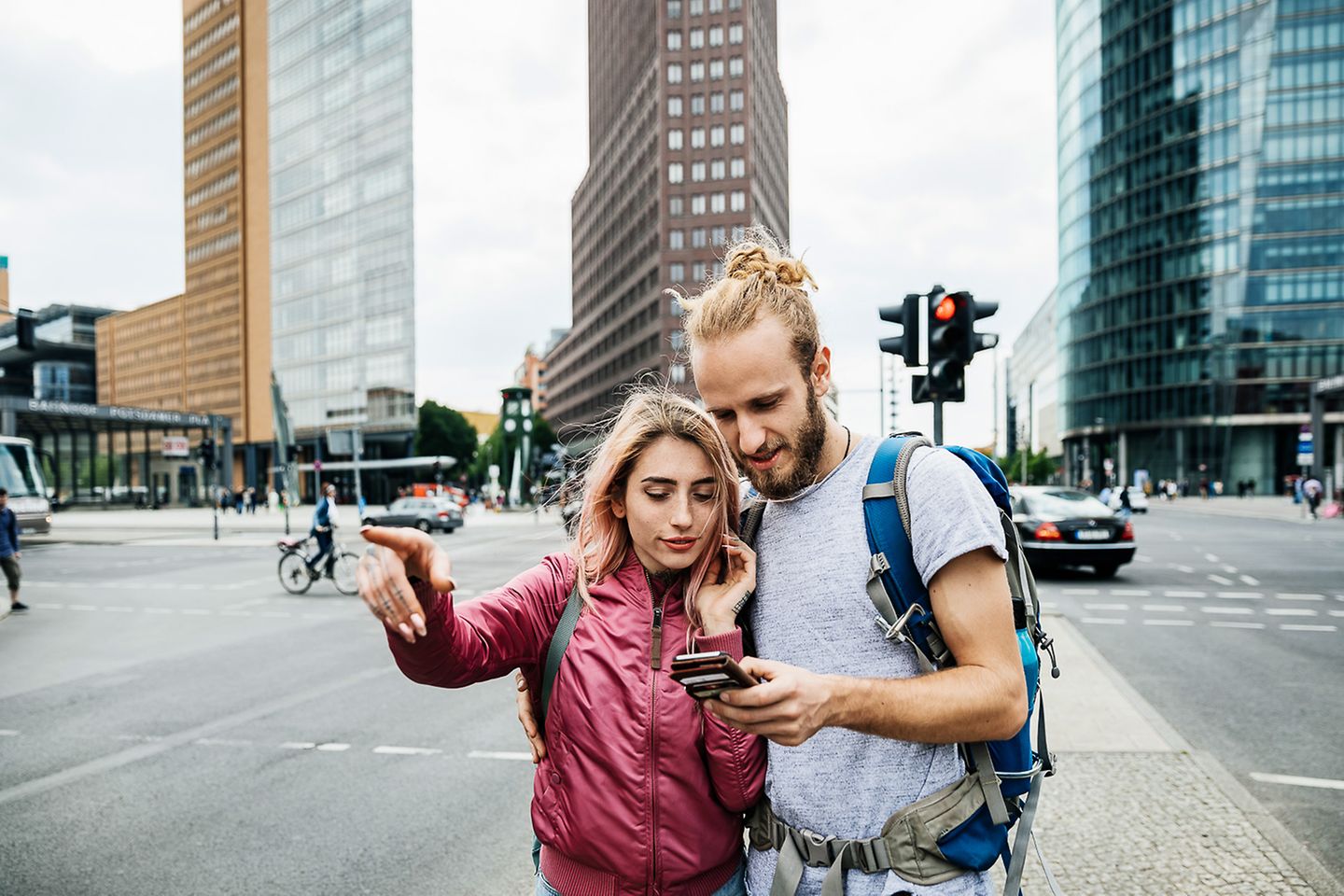 Un jeune couple se trouve à un carrefour et regarde un smartphone.