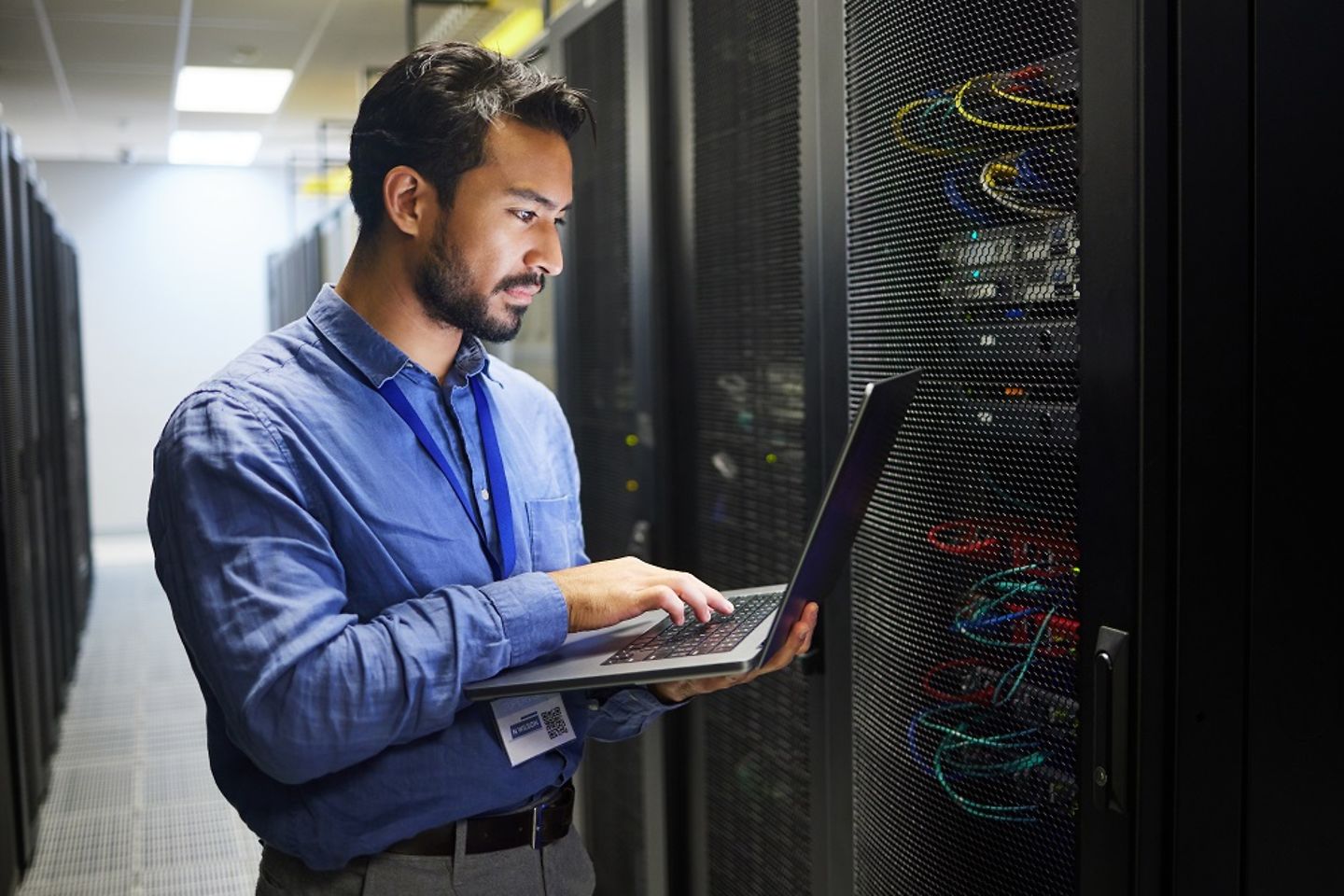 IT-Mitarbeiter mit Laptop prüft einen Server im Rechenzentrum