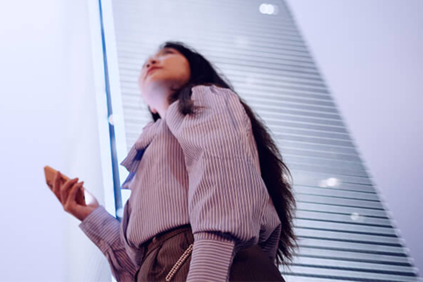 Mujer con smartphone mirando unos rascacielos de oficinas