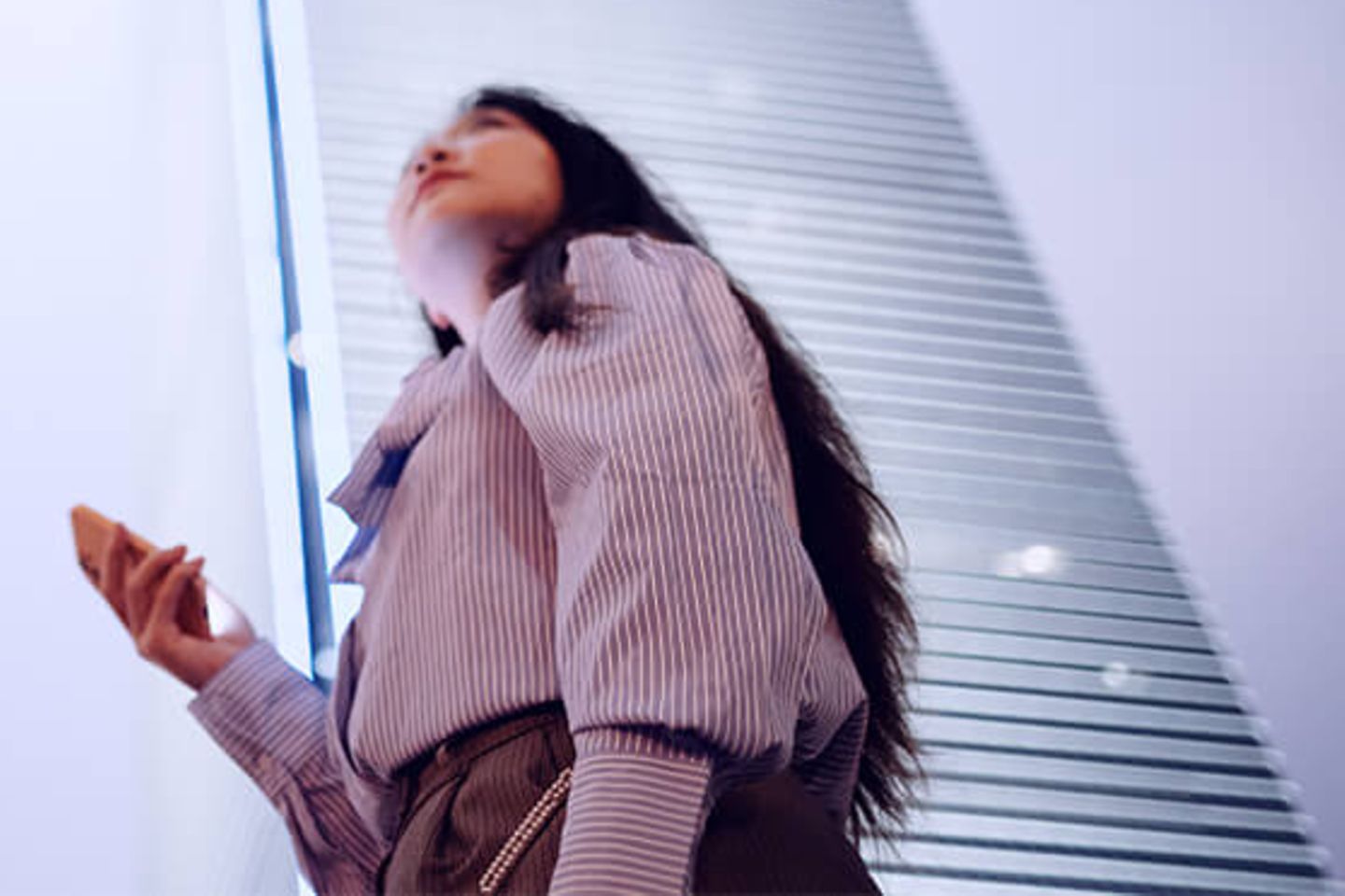 Woman with smartphone looking up to office skyscrapers