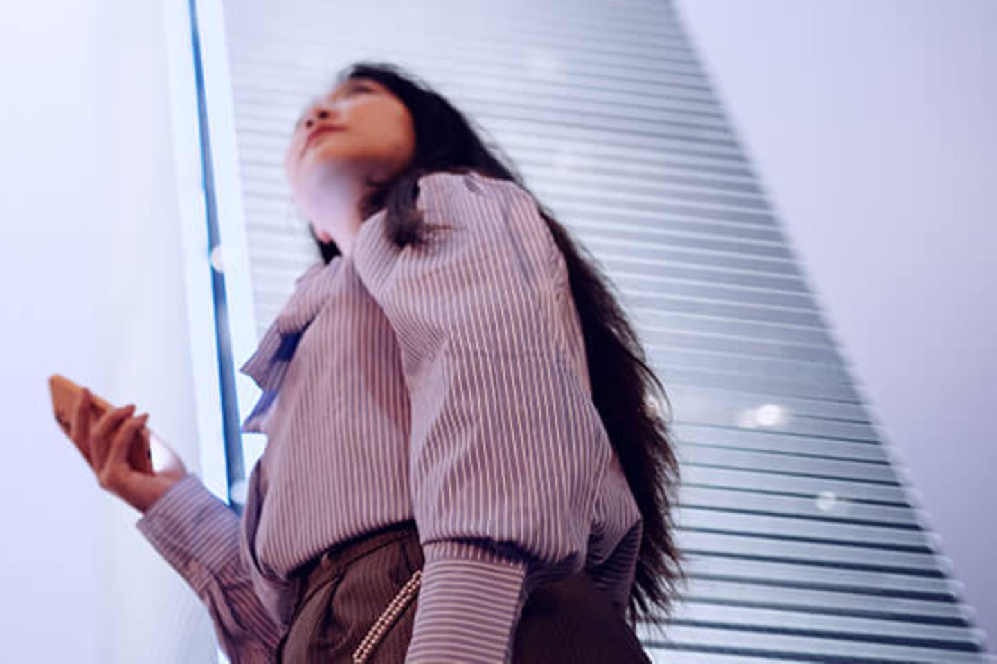 Woman with smartphone looking up to office skyscrapers