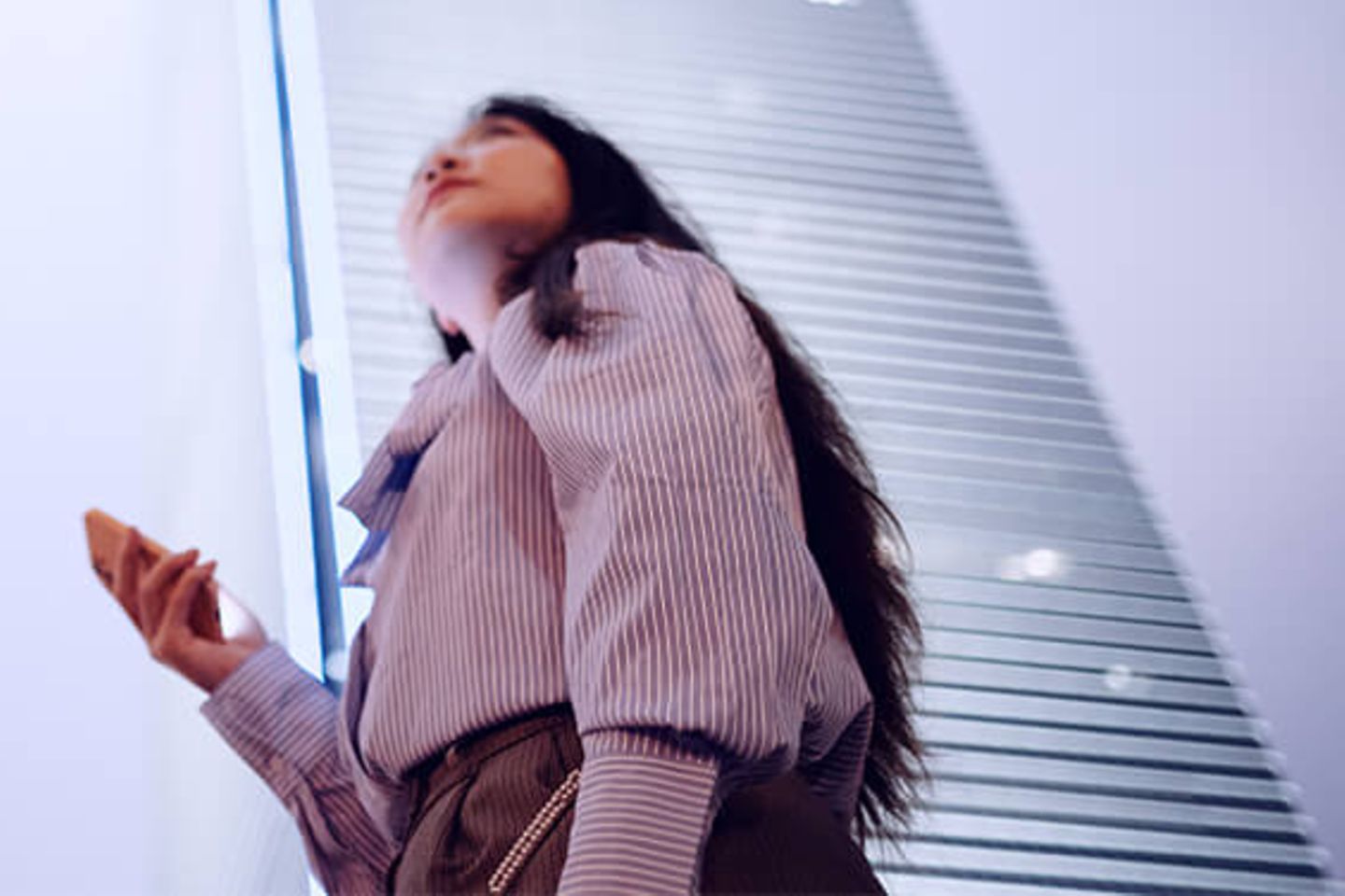 Woman with smartphone looking up to office skyscrapers