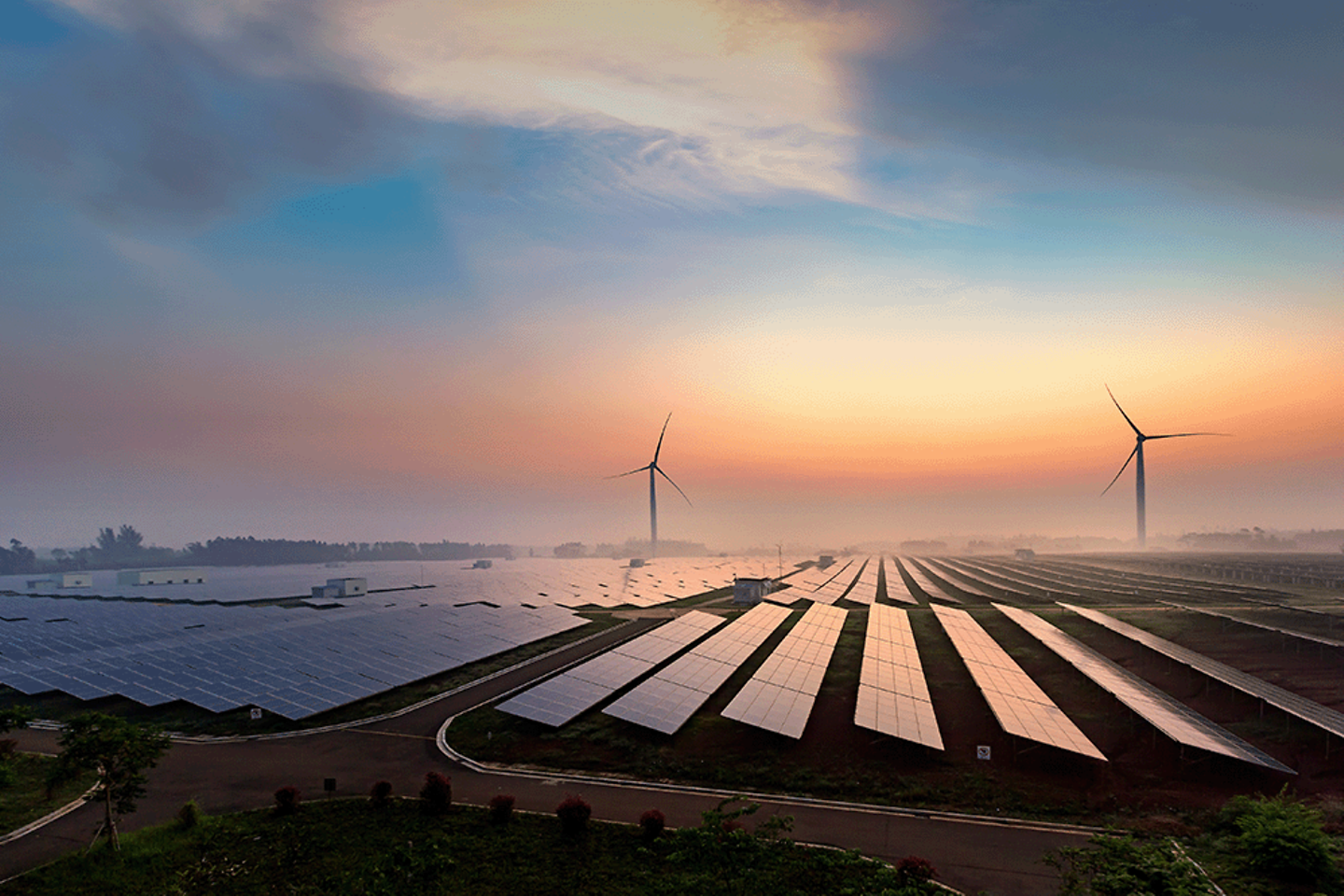 Sunrise above solar panels and wind turbines