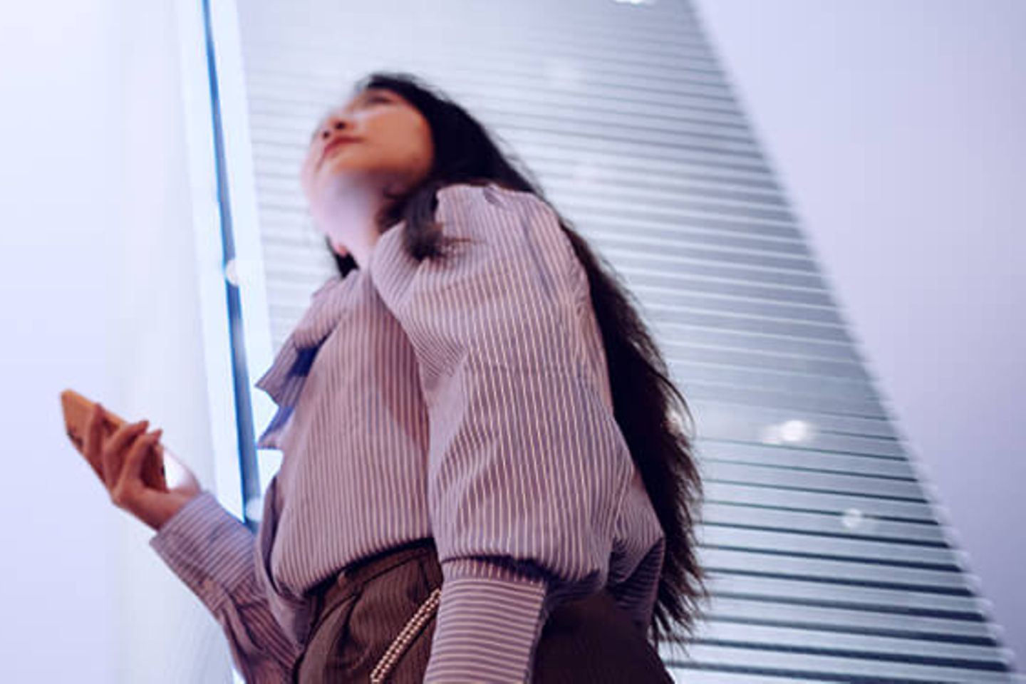 Woman with smartphone looking up to office skyscrapers