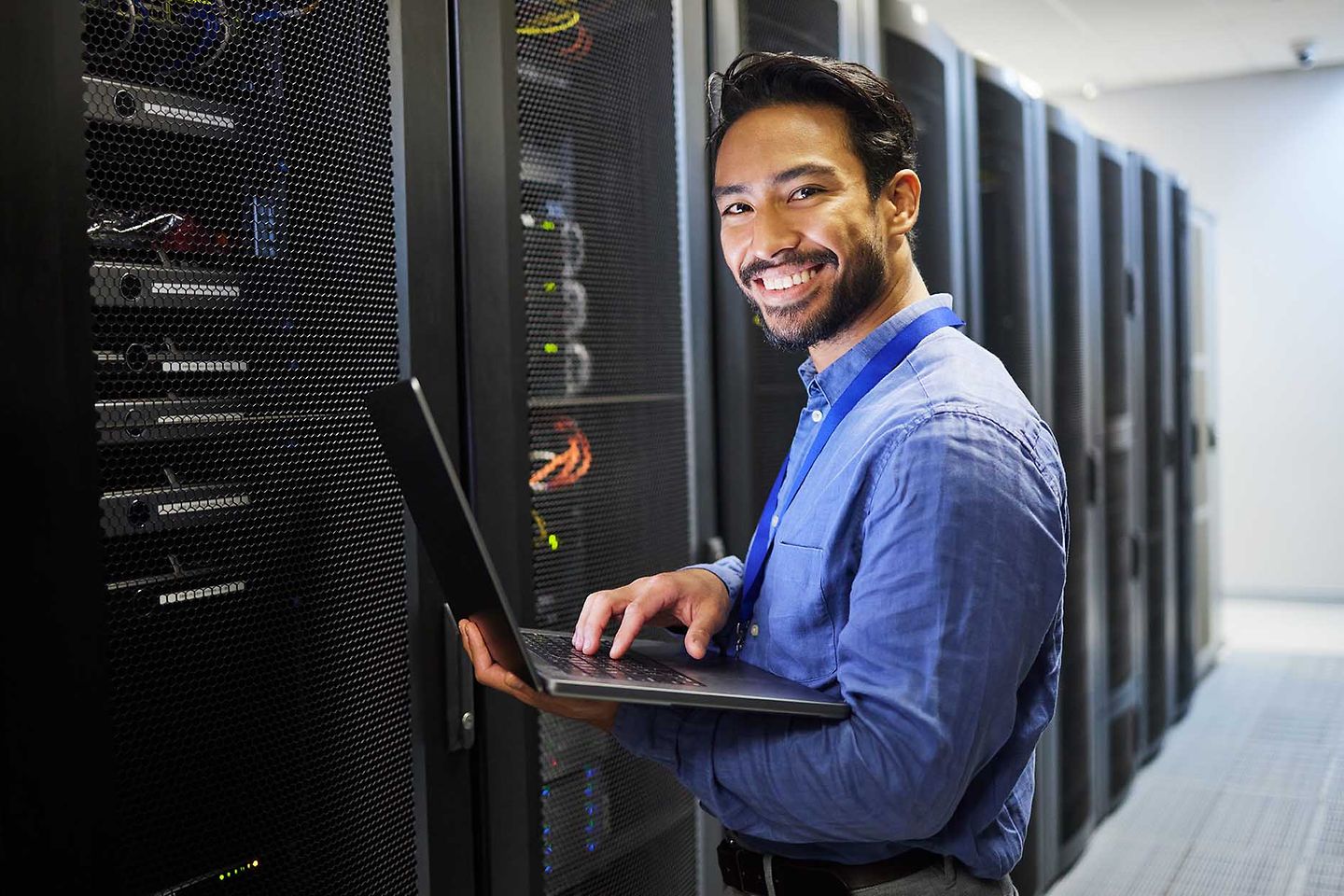 Software engineer in data server room with laptop
