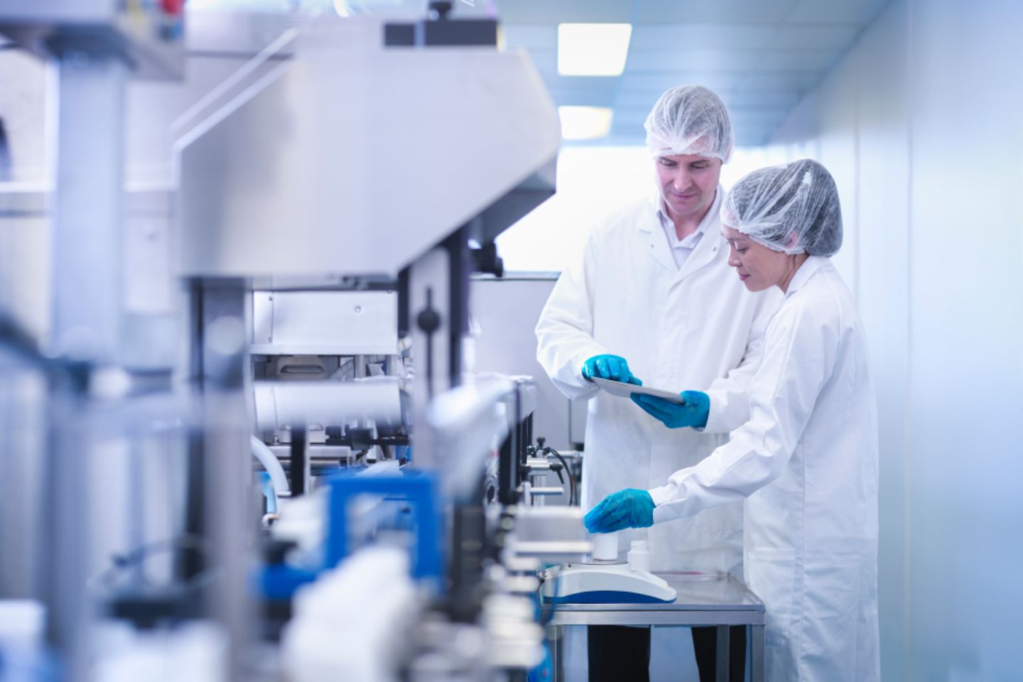 Operadores inspecionam um produto em uma fábrica de produtos farmacêuticos.
