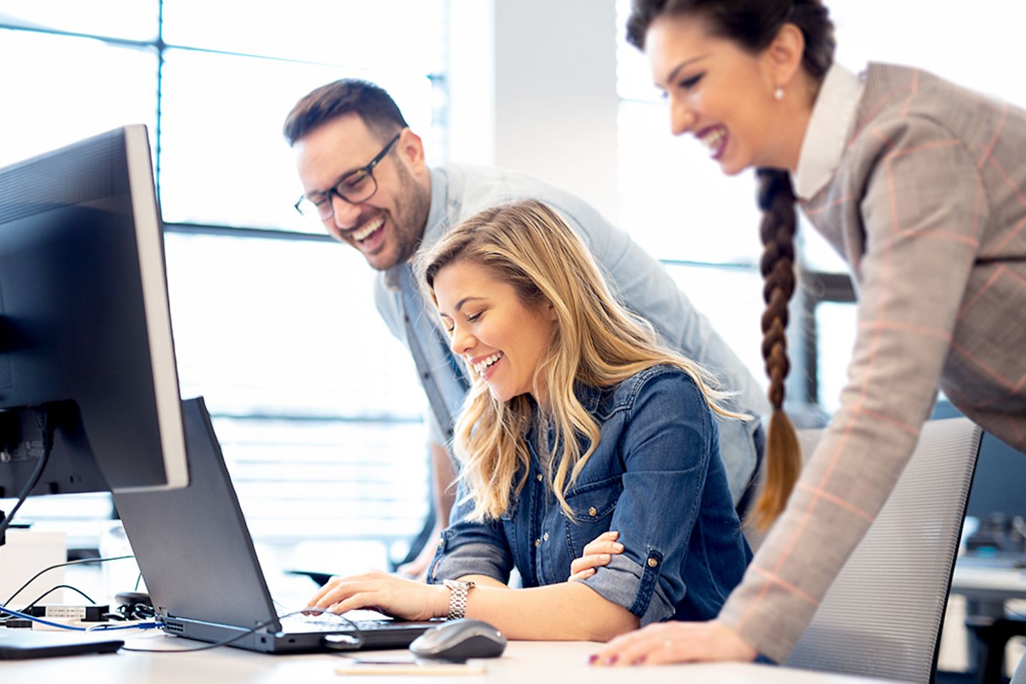 Happy team going over a project together at a computer.