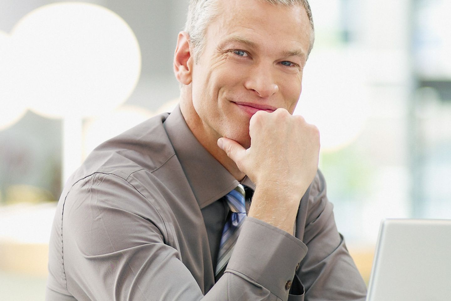 Businessman sits at laptop and smiles into camera