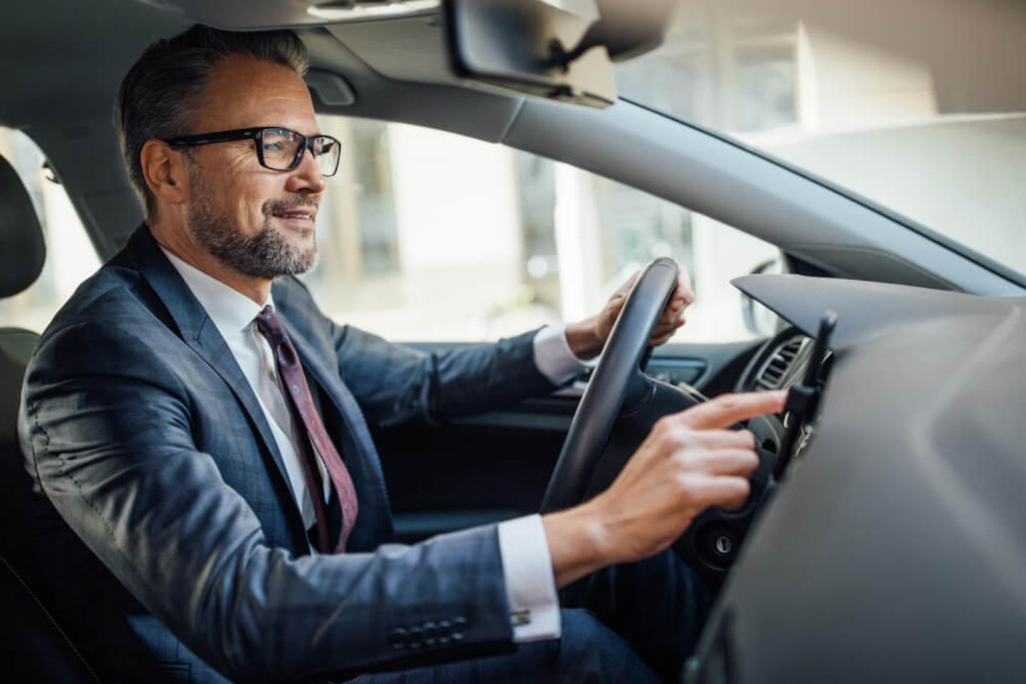 Hombre de negocios sentado en su coche y abriendo el sistema de navegación de su smartphone