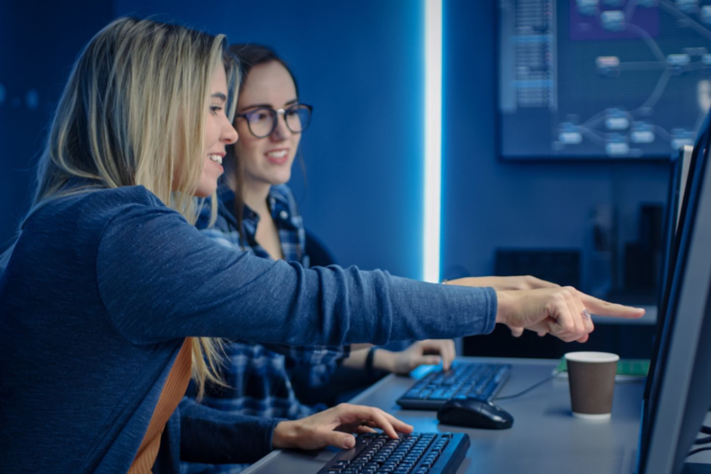 Duas mulheres programadoras de TI trabalhando em um computador de mesa em um centro de dados