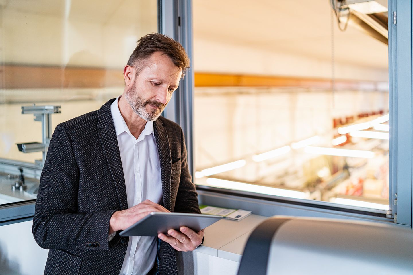 Man looks at a tablet, which he holds in his hand.