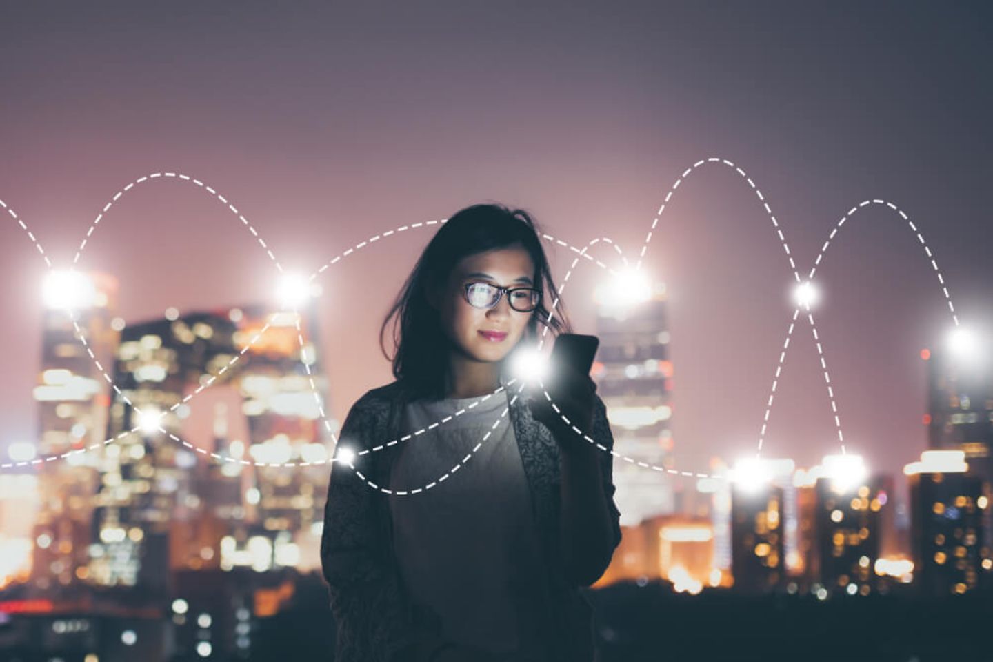 Femme avec un smartphone devant un ciel nocturne