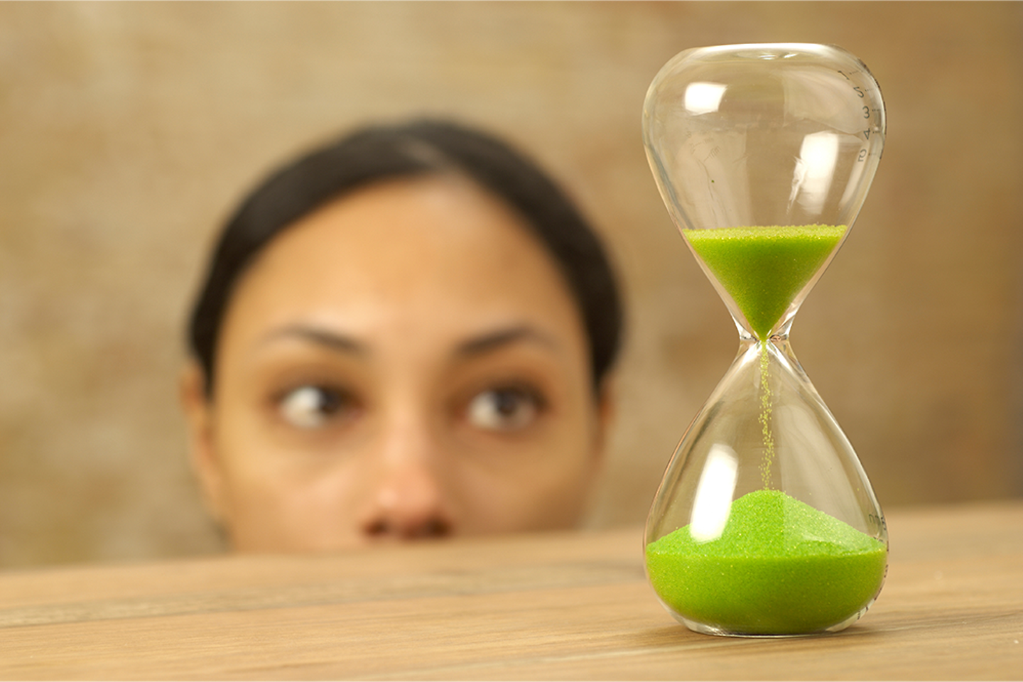 Woman looking at hourglass with green sand