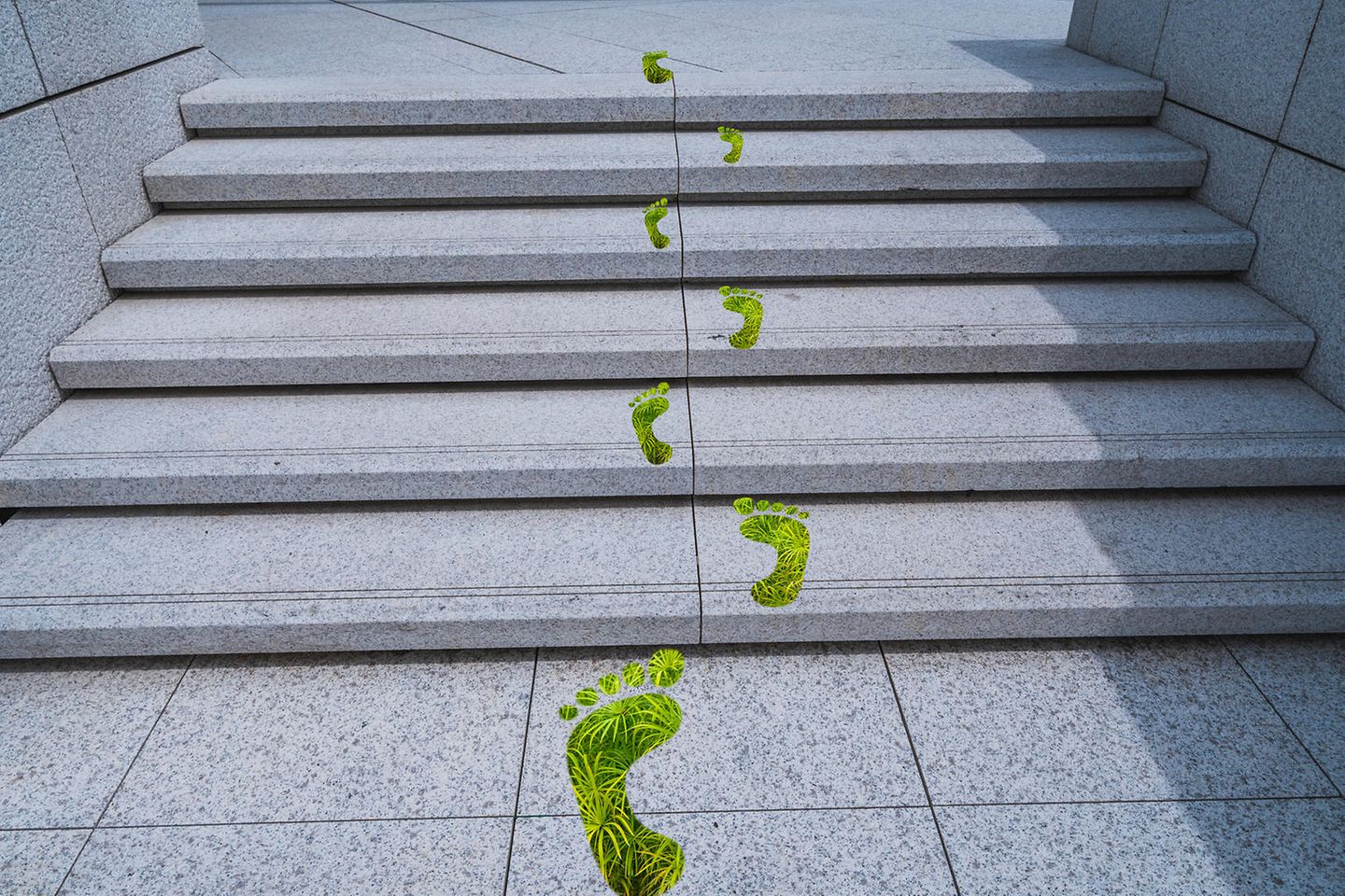 green footprints leading up concrete stairs