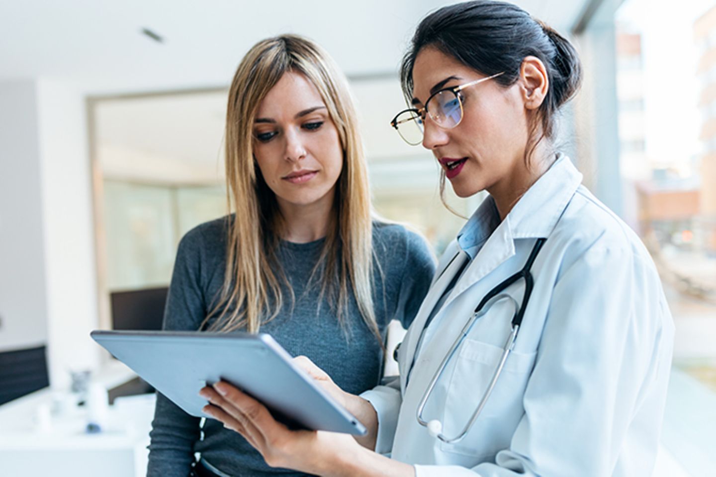 Eine Ärztin erklärt einer Patientin mit einem digitalen Tablet eine Behandlung