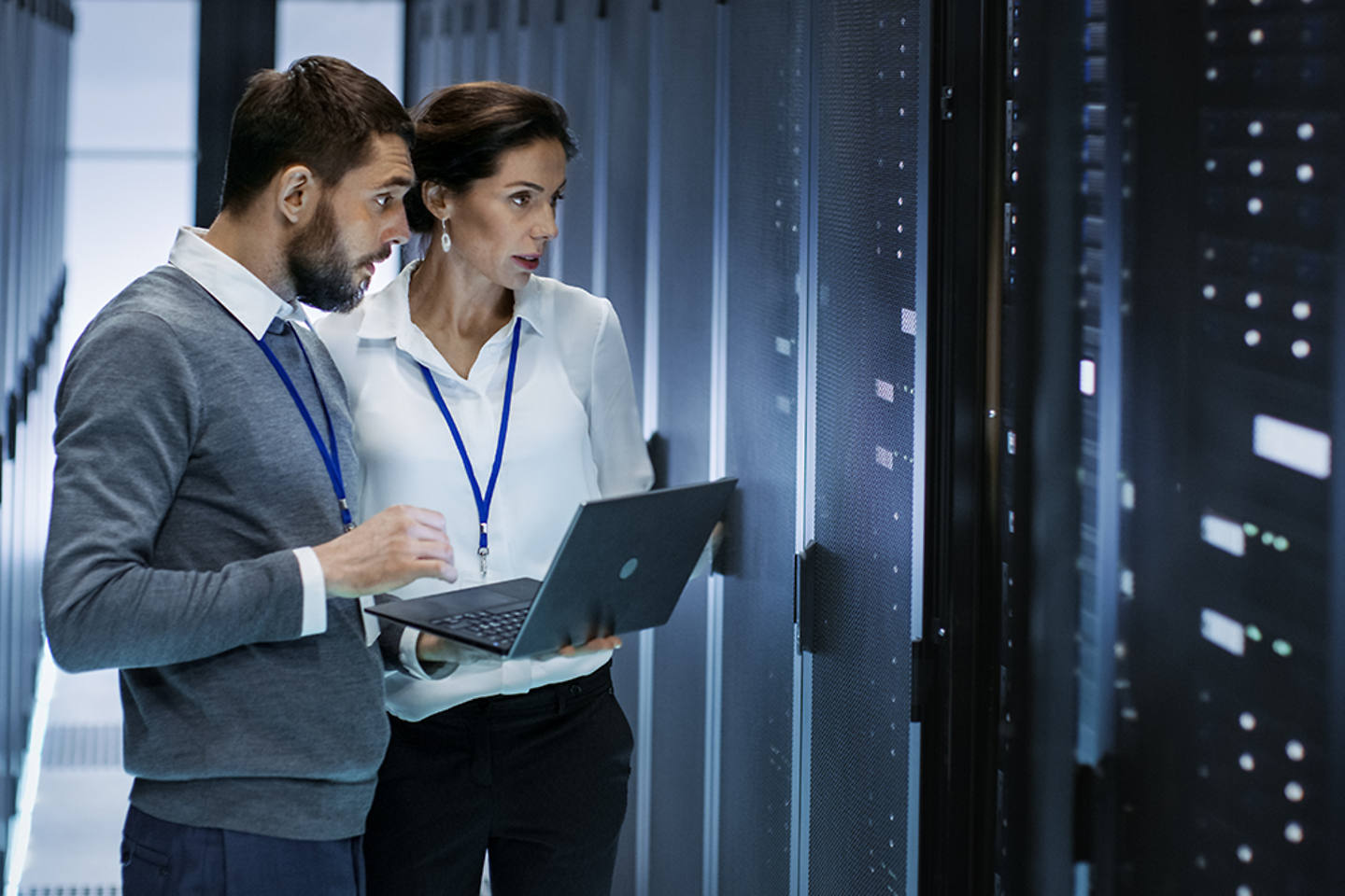 Male IT Specialist Holds Laptop and Discusses Work with Female Server Technician.