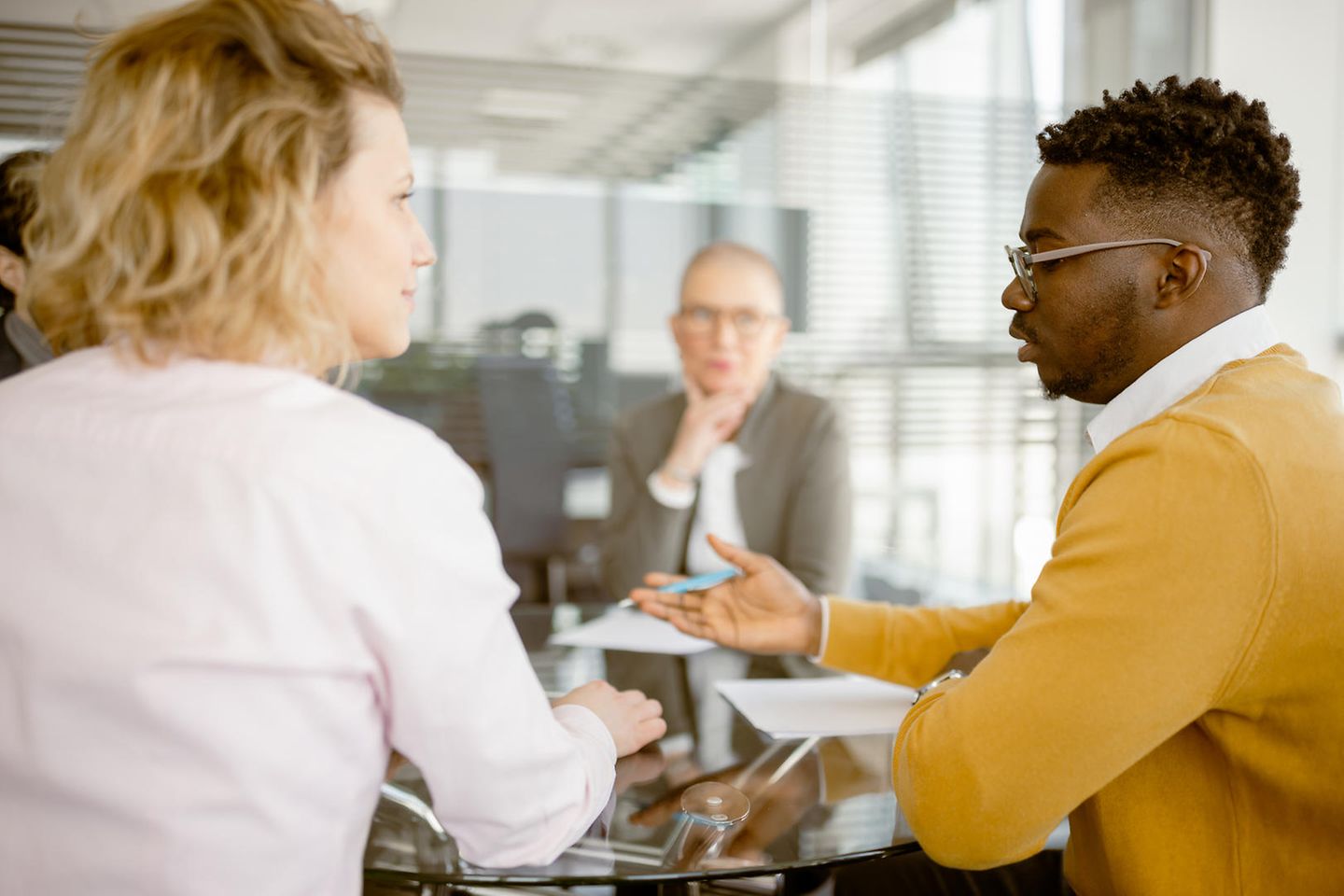 Drei Menschen sitzen im Büro und unterhalten sich