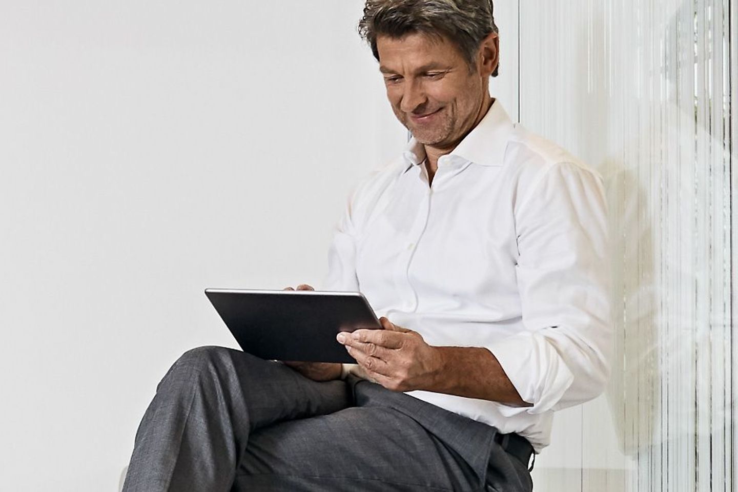 Mann sitzt mit einem Tablet in der Wohnung