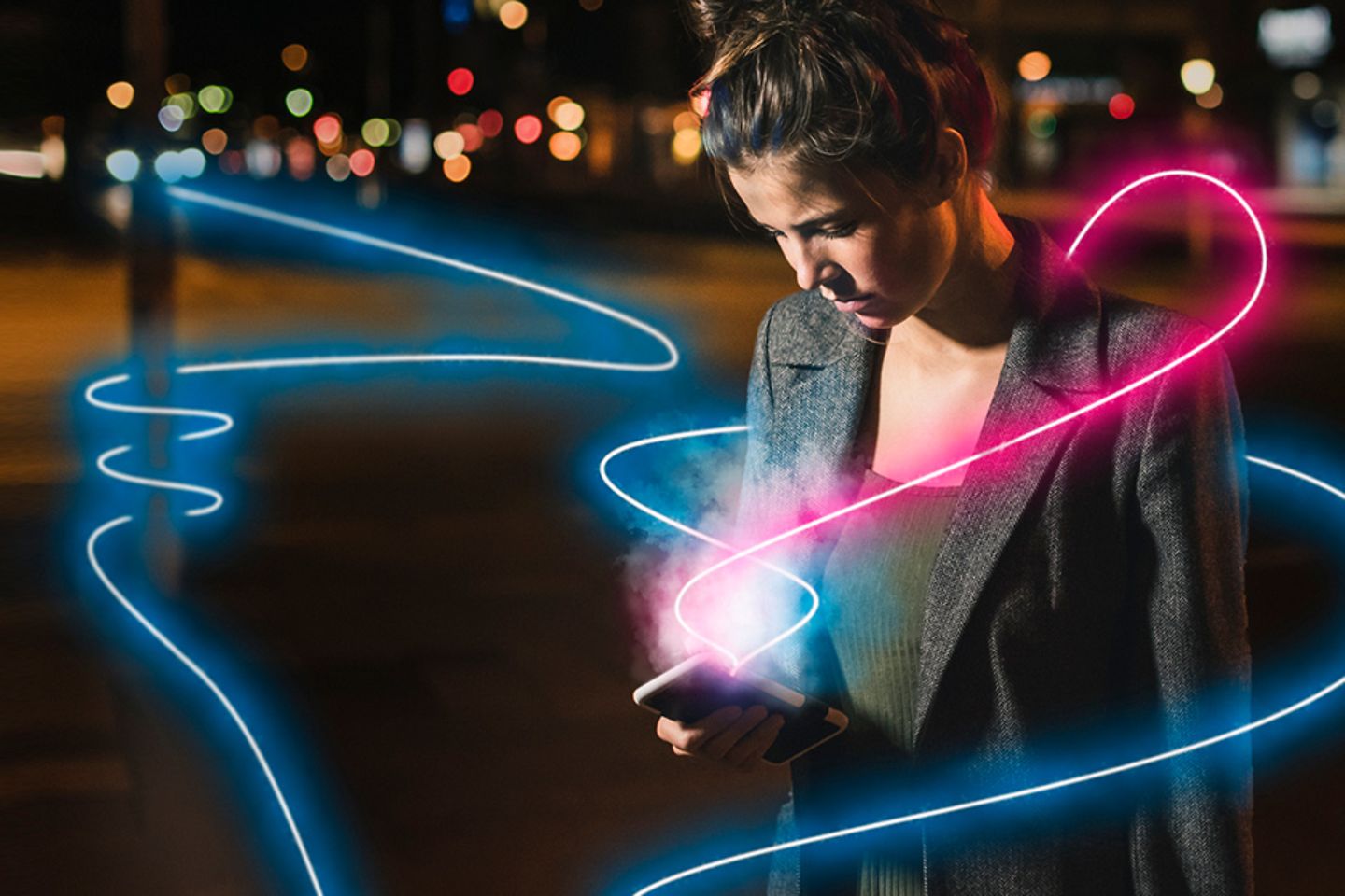 Frau steht auf nächtlicher Straße und blickt auf ihr leuchtendes Smartphone. Pinke und blaue Leuchtspuren umgeben sie.