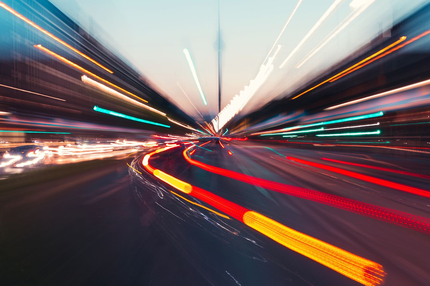 Langzeit belichtetes Foto einer Straße mit Lichtern und Verkehr in der Dämmerung.