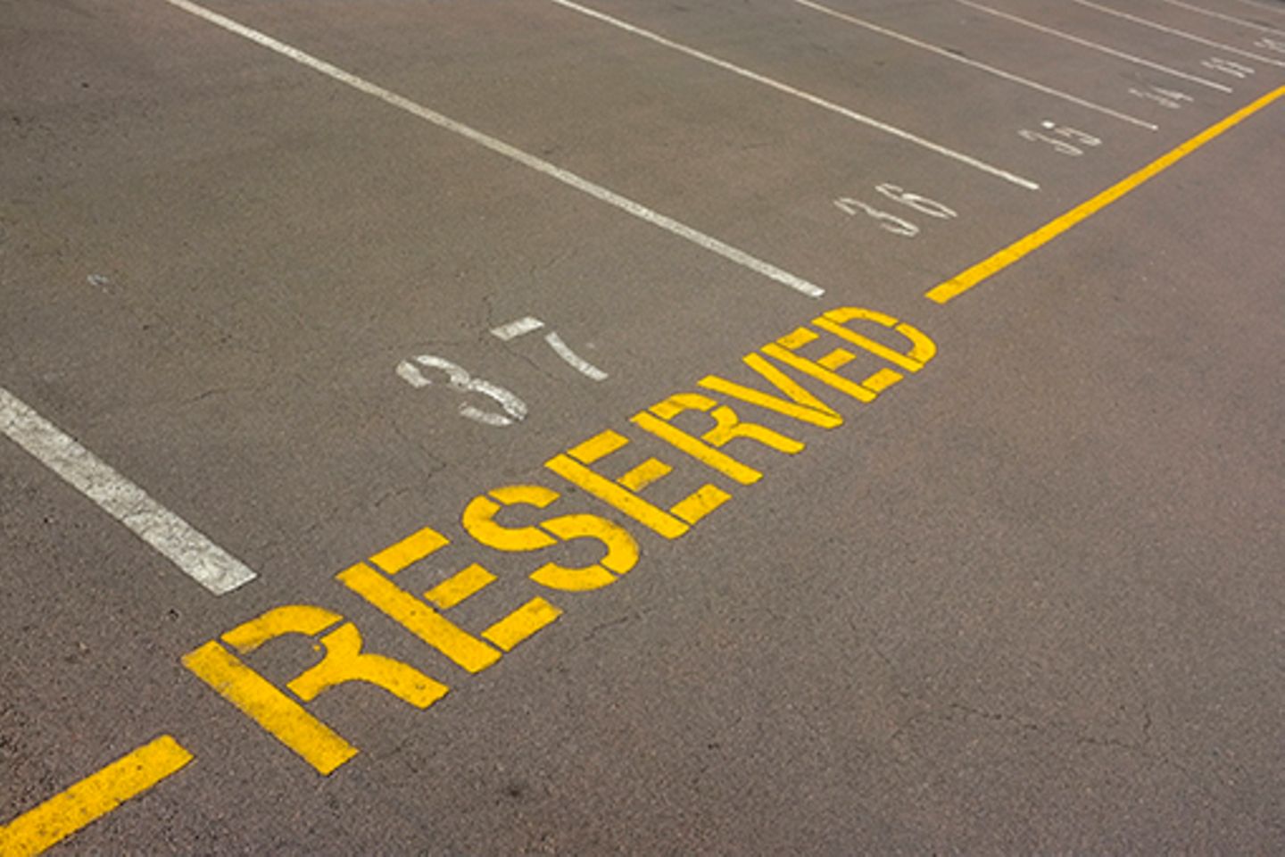 Photo of empty parking spaces, one with the inscription "reserved".