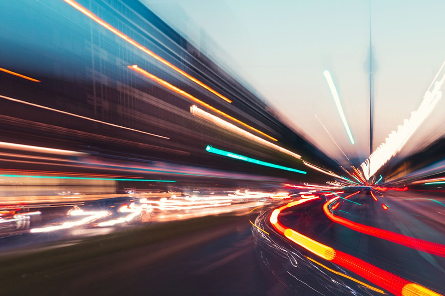 Langzeit belichtetes Foto einer Straße mit Lichtern und Verkehr in der Dämmerung.