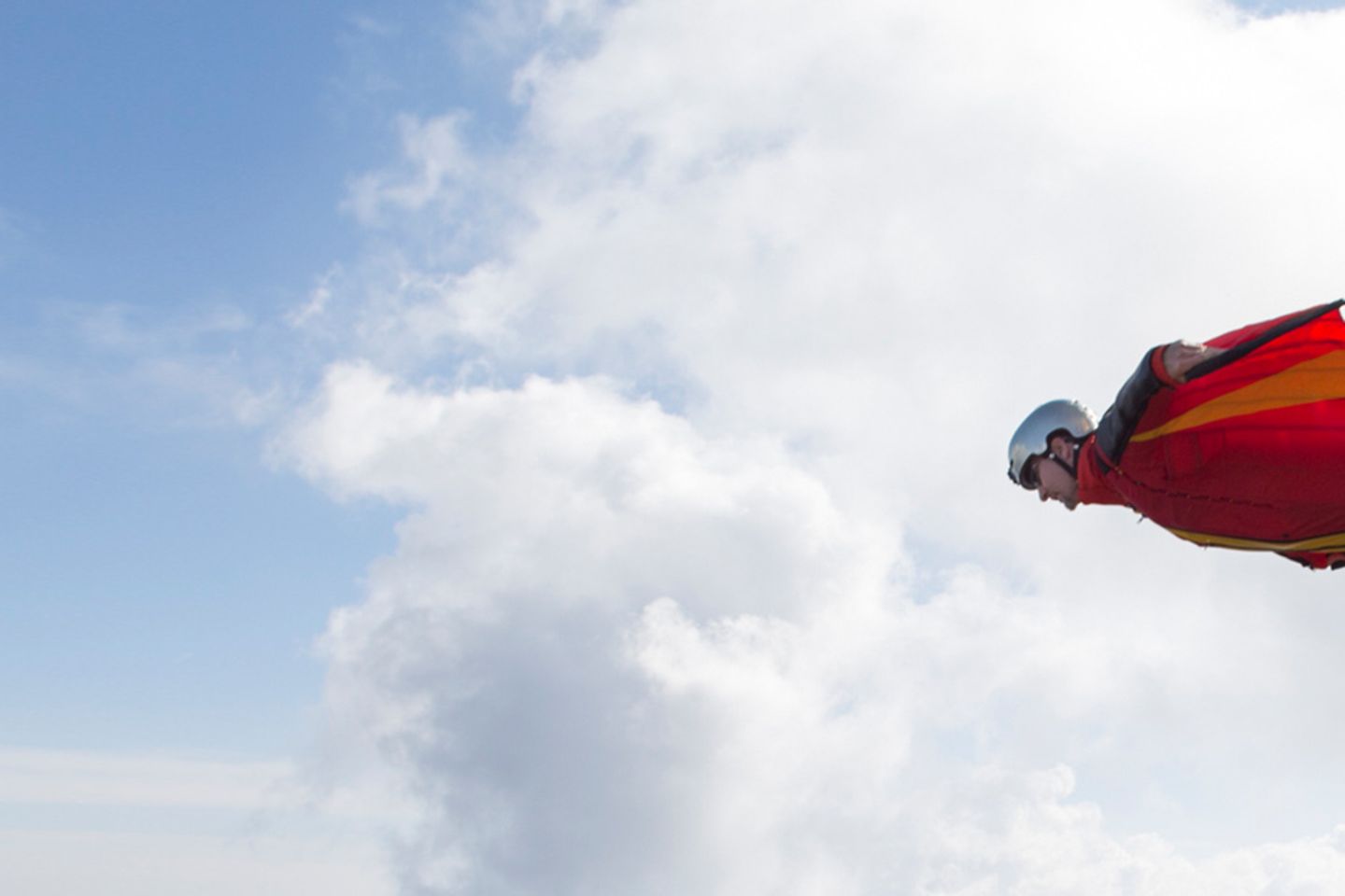 Wingsuit Jumper springt mit rotem Leuchtfeuer von Felsen.