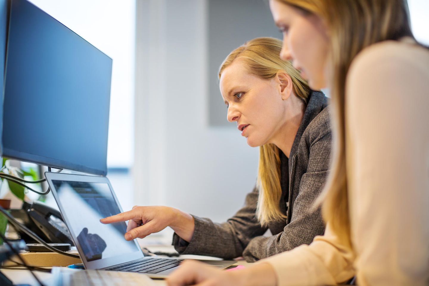 Two women are sitting in front of a tablet.