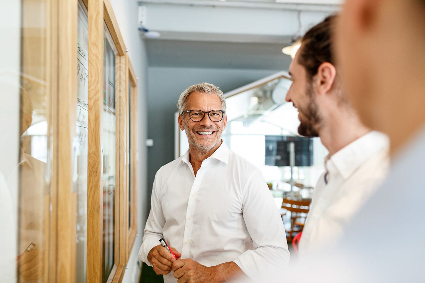 Un homme d’affaires souriant dans un bureau devant des collaborateurs