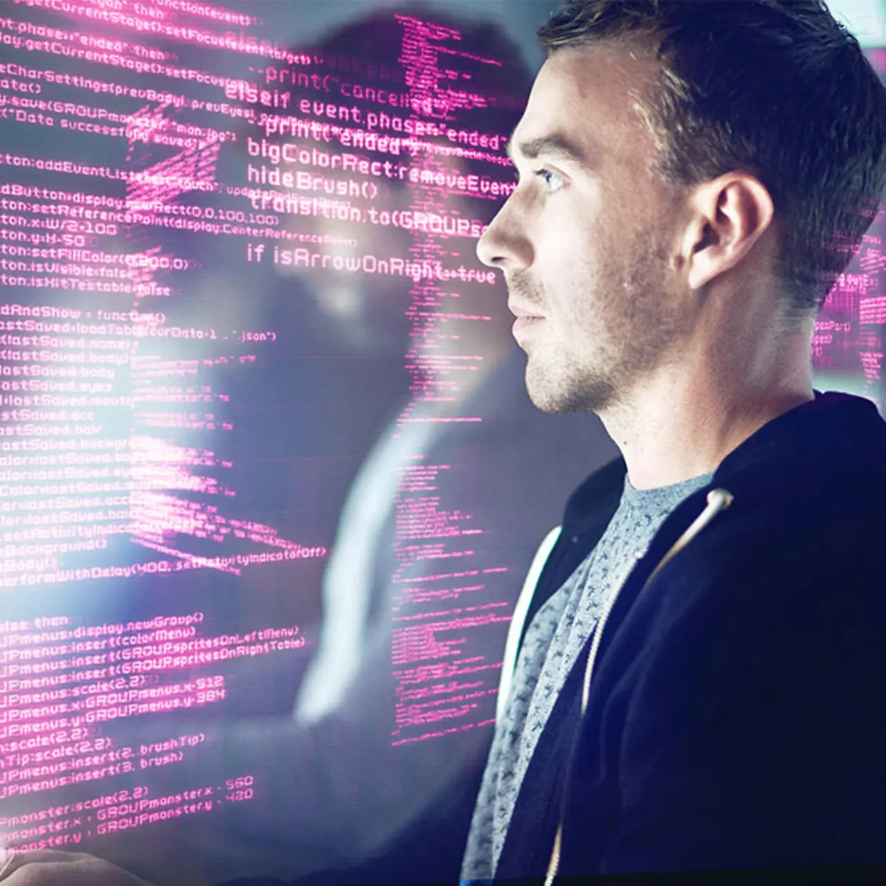 A man sitting infront of a screen with coding everywhere in magenta 