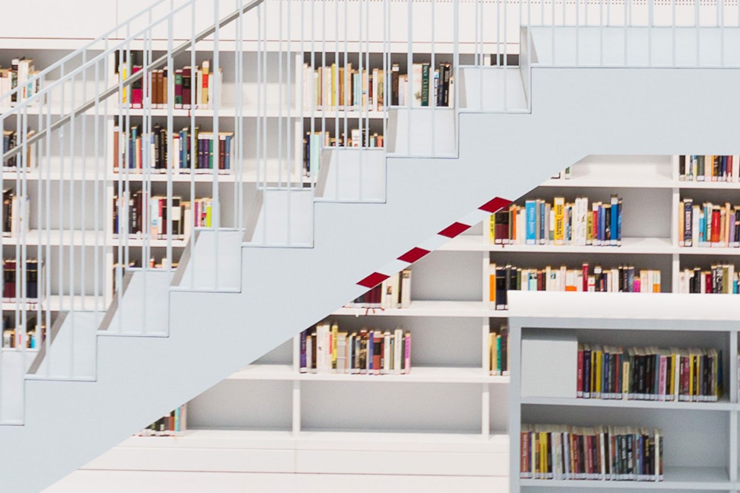 Helle Bibliothek mit vielen Bücherregalen und einer Treppe